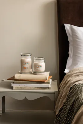 two afternoon scrapbooking candles on bedside table with books