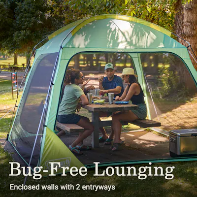 Four people seated at a camp table that is inside of a tent