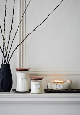 three woodwick linen candles in various sizes on mantle
