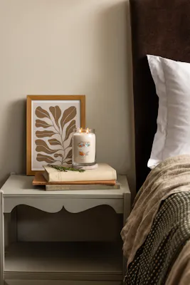 afternoon scrapbooking candle on bedside table with books and artwork