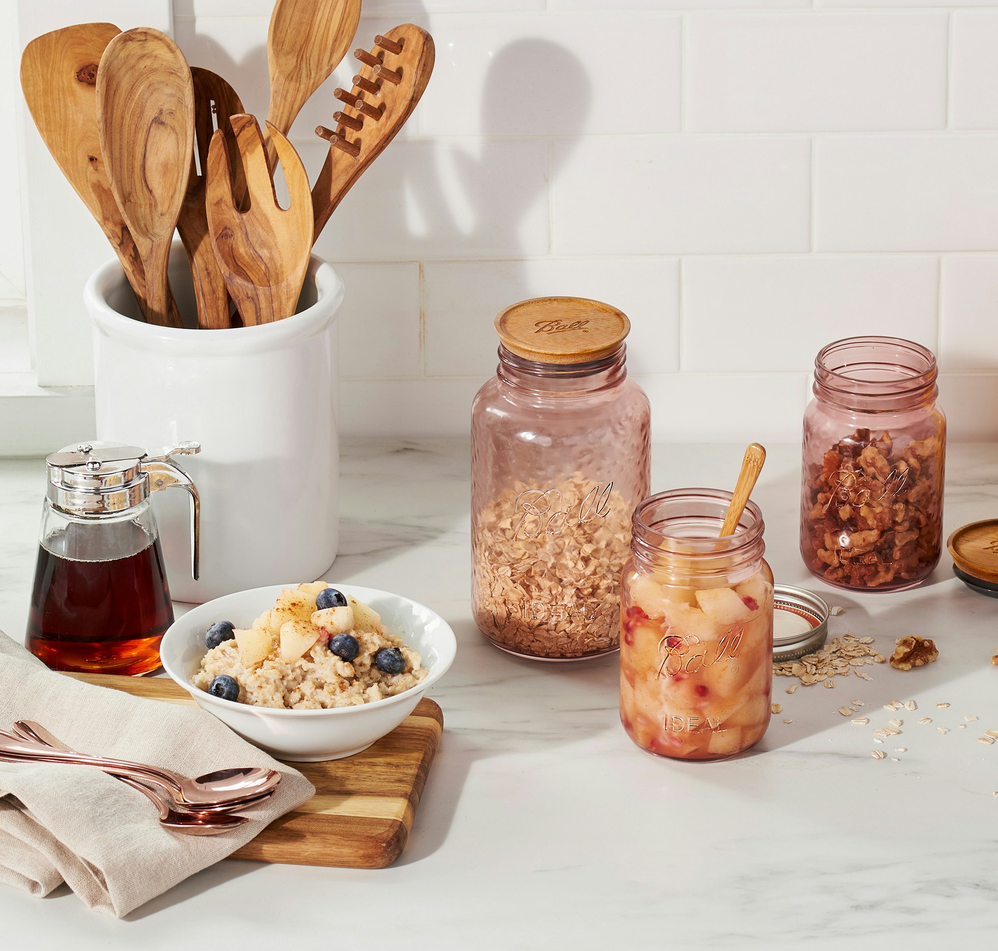 Breakfast prep on kitchen counter with an array of Ball jars filled with fruit, oatmeal and granola